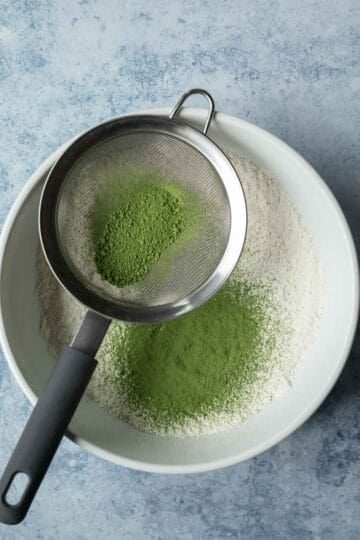 Sifting matcha into a mixing bowl with the flour.