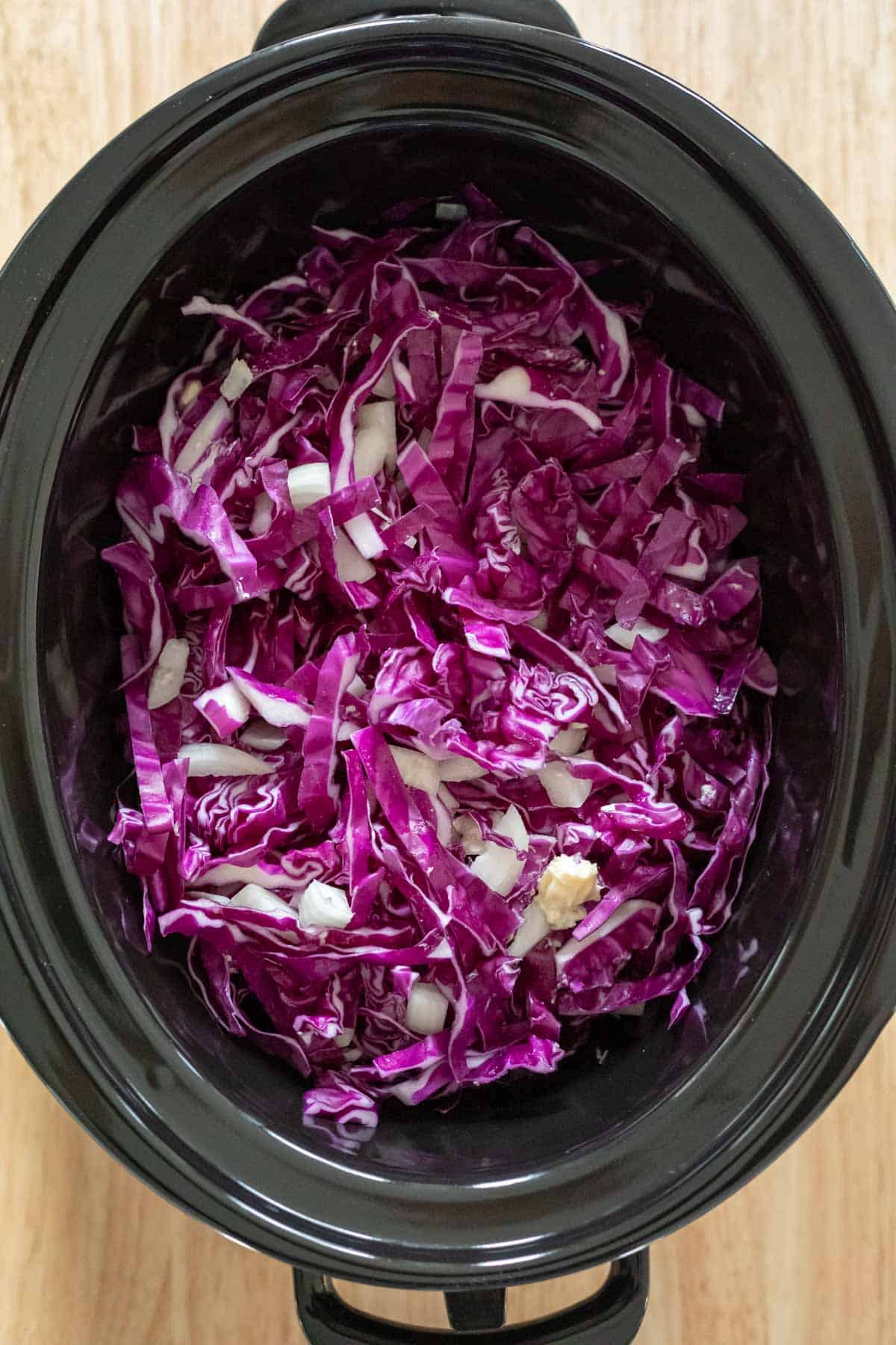 Freshly shredded red cabbage inside a slow cooker.