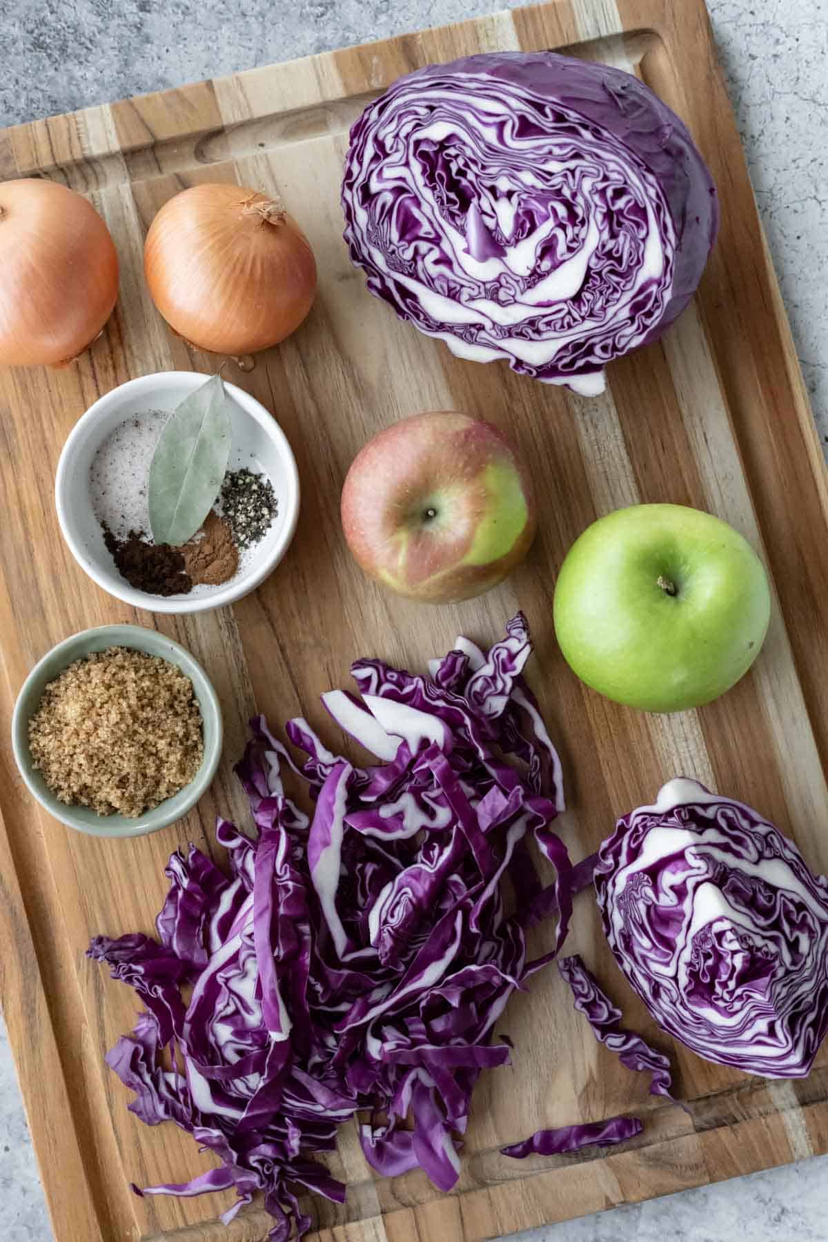 Ingredients needed for Rotkohl laid out on a wood cutting board.