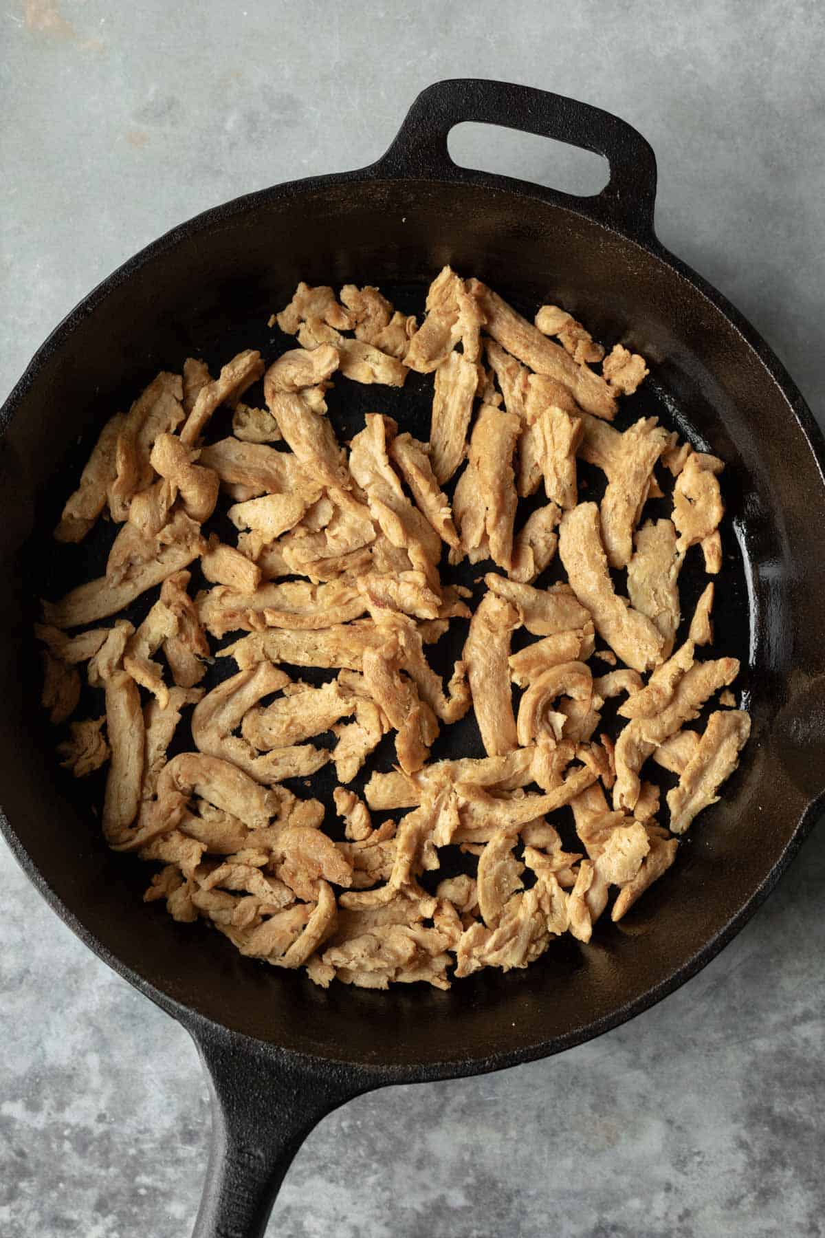 Chicken-style soy curls cooking in a skillet.