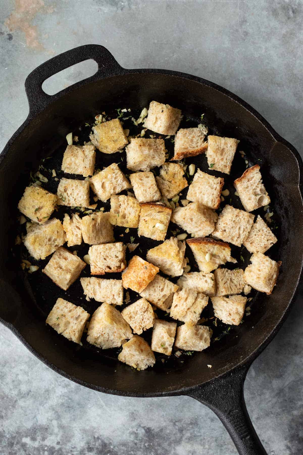 Sourdough bread cubes toasting in a skillet.