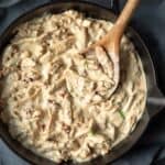 close-up overhead of vegan marry me chicken in a skillet with a wooden spoon scooping some out.