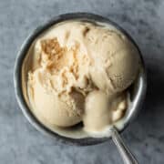 overhead of a single serving of vegan protein ice cream in a silver dish with a spoon.