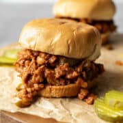 Chunky soy curl vegan sloppy joes on buns with sliced pickles.