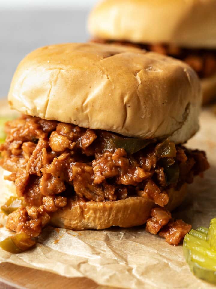 Chunky soy curl vegan sloppy joes on buns with sliced pickles.