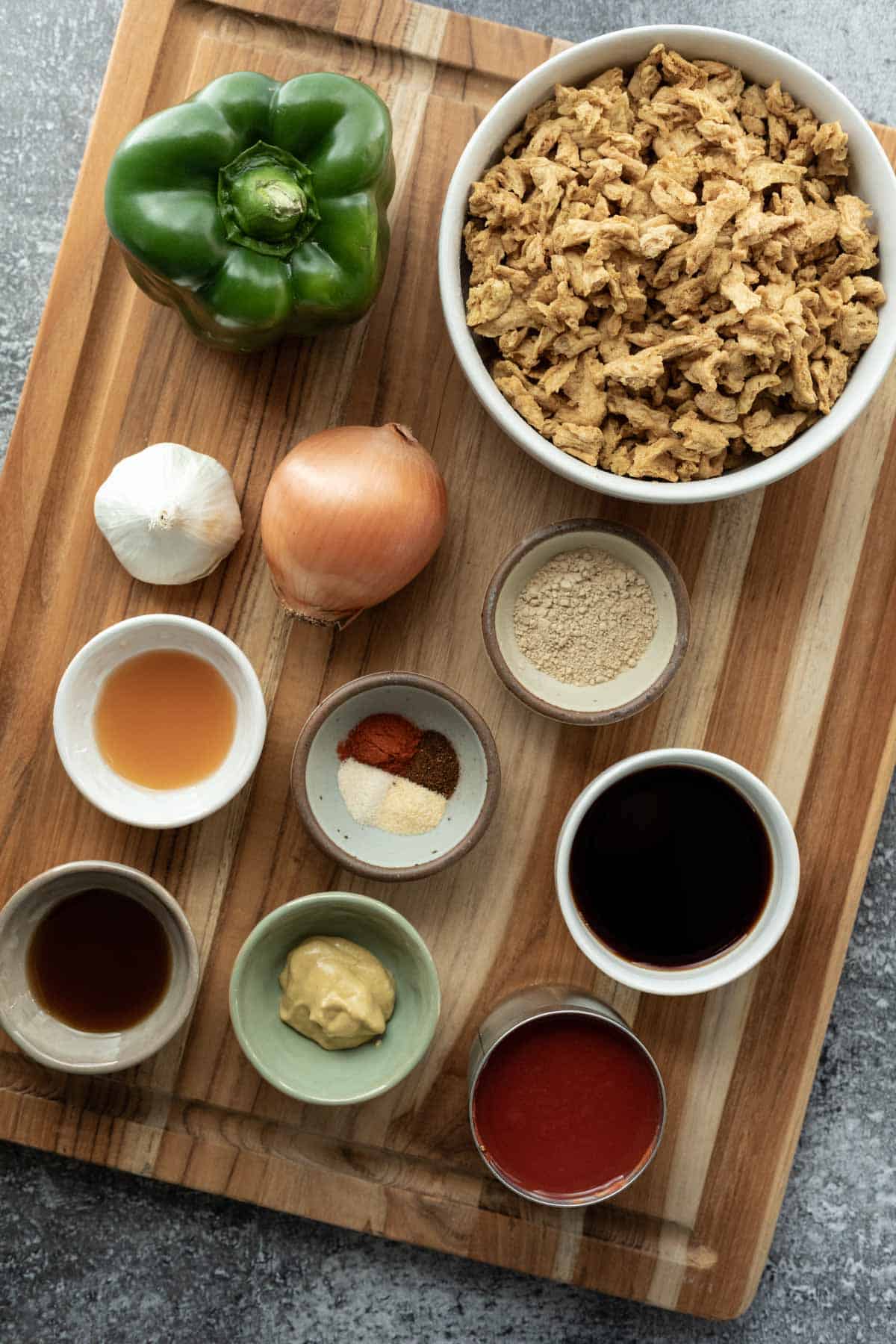Ingredients needed for vegan sloppy joes laid out on a wood cutting board.