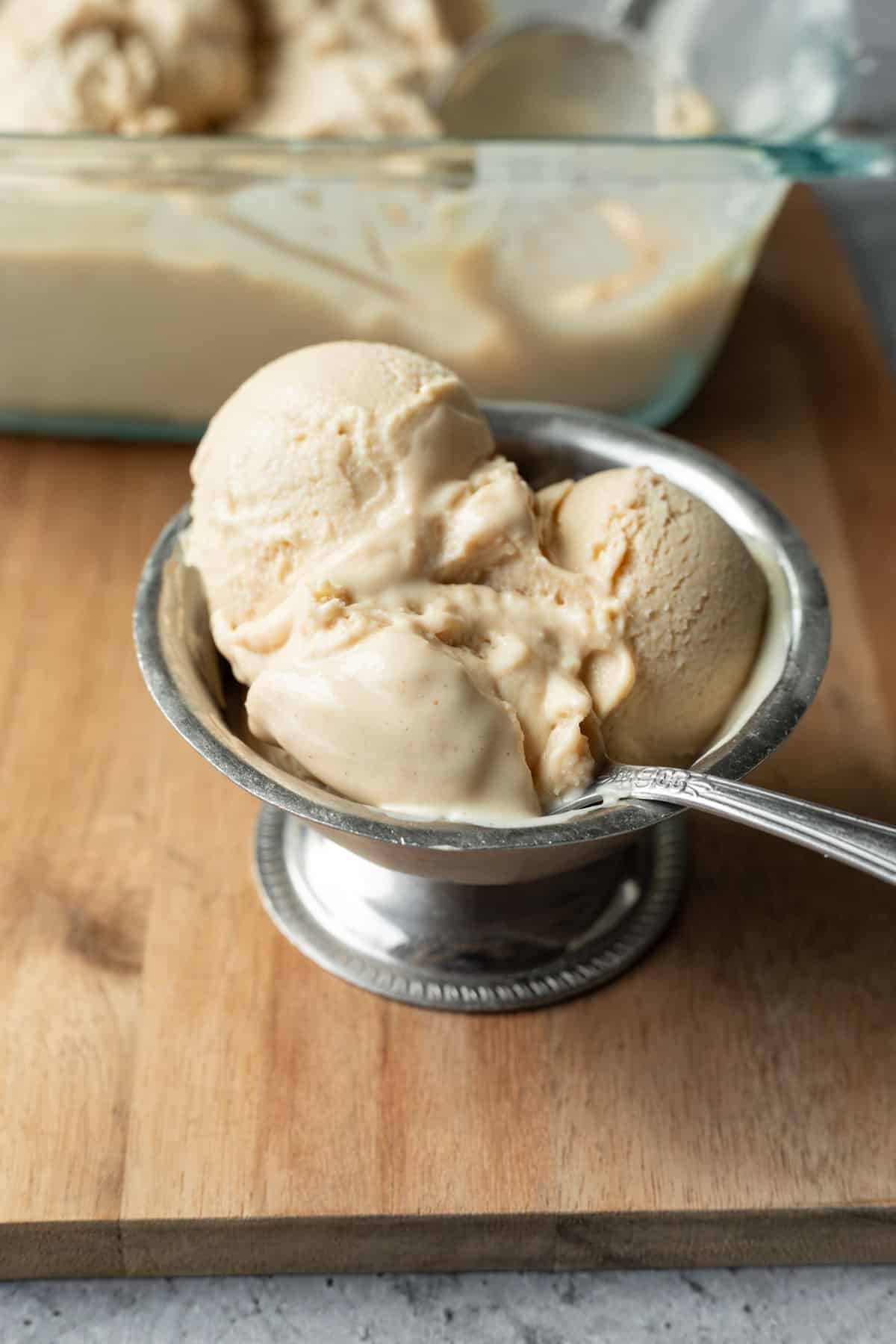A serving of vegan tofu ice cream in a silver dish with the rest in the background.