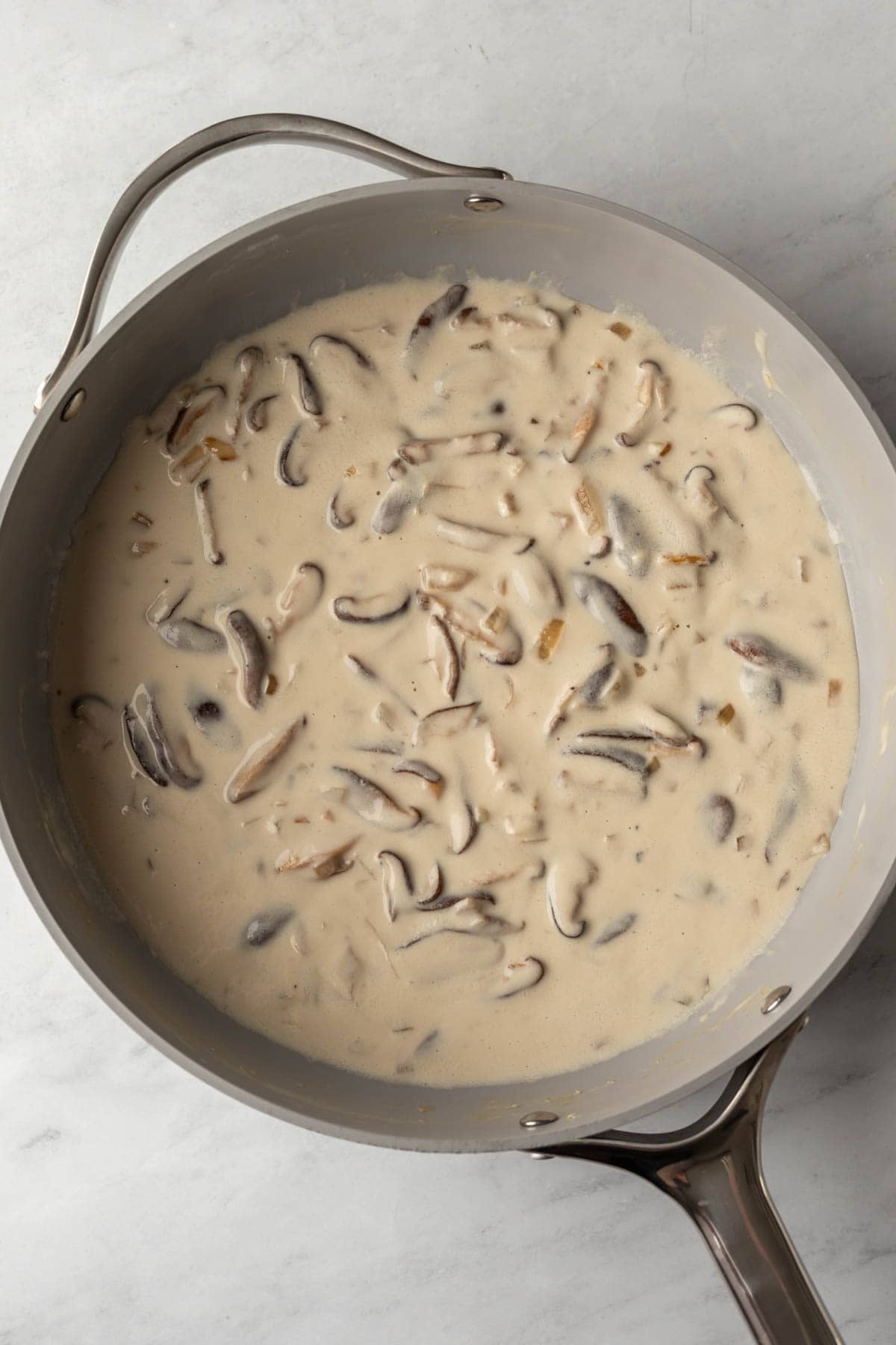 sunflower seed cream sauce and shiitake mushrooms in a sauté pan.