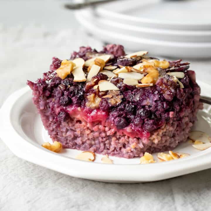 A square of millet breakfast casserole with berries resting on a small plate.