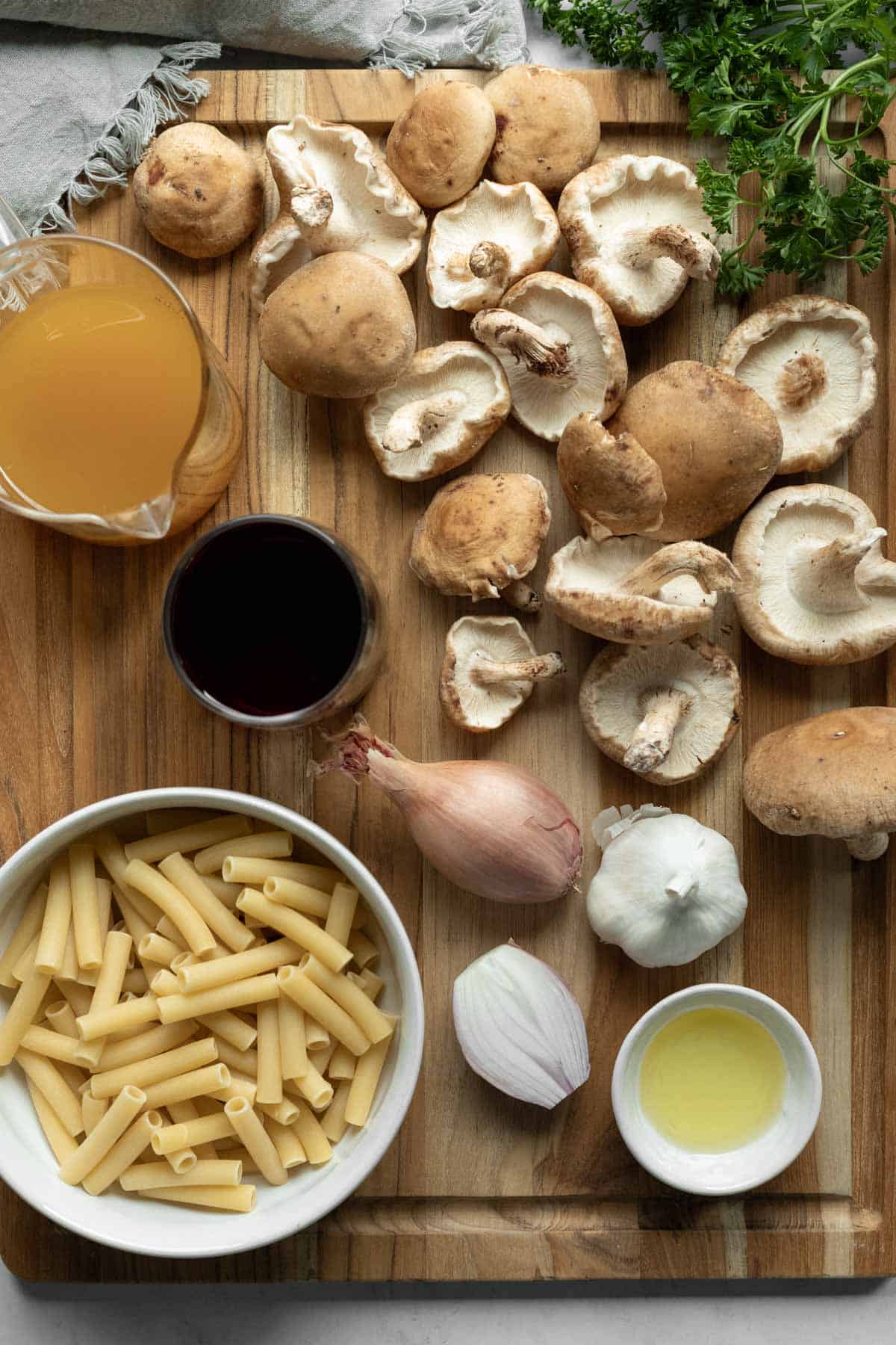 Ingredients needed for shiitake mushroom pasta laid out on a wooden board.