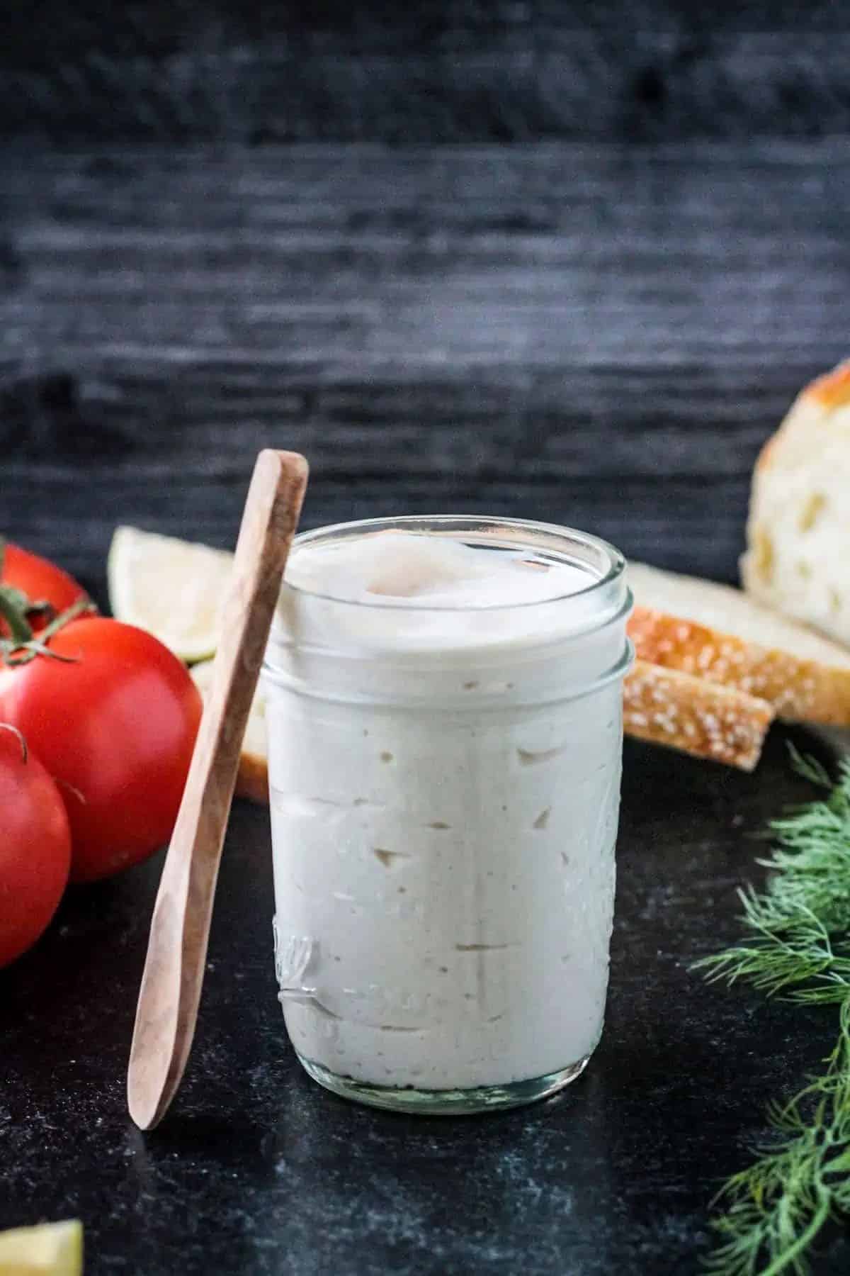 vegan mayo in a mason jar with a wooden spoon next to it.