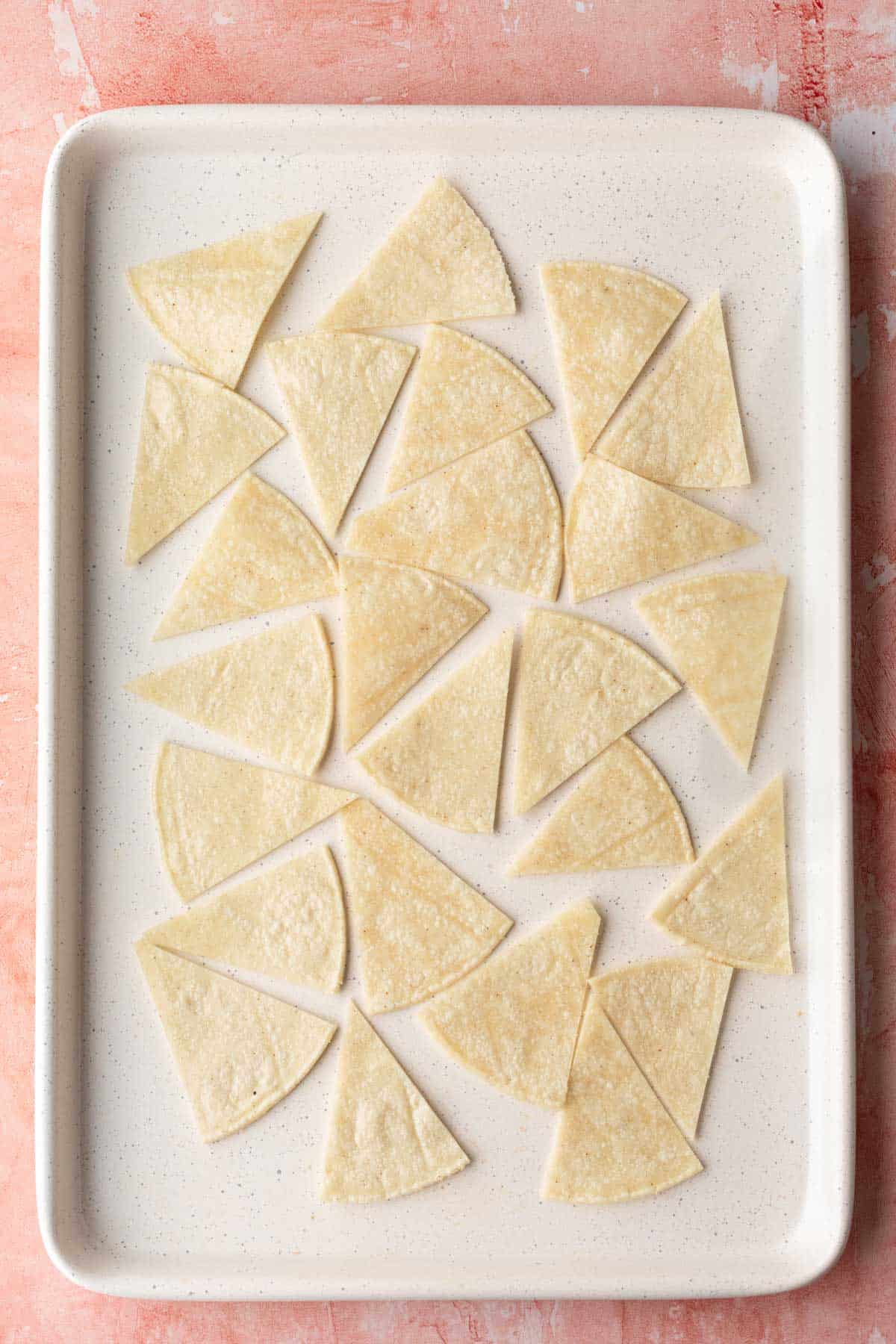 overhead shot of tortilla chips on a baking sheet.