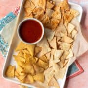 overhead of air fryer tortilla chips on a baking tray with salsa.