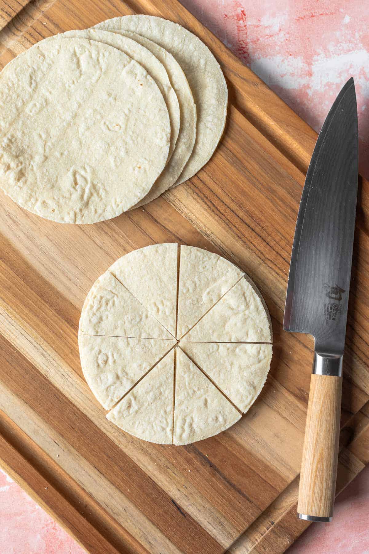 cutting the tortillas into wedges on a wooden board. 