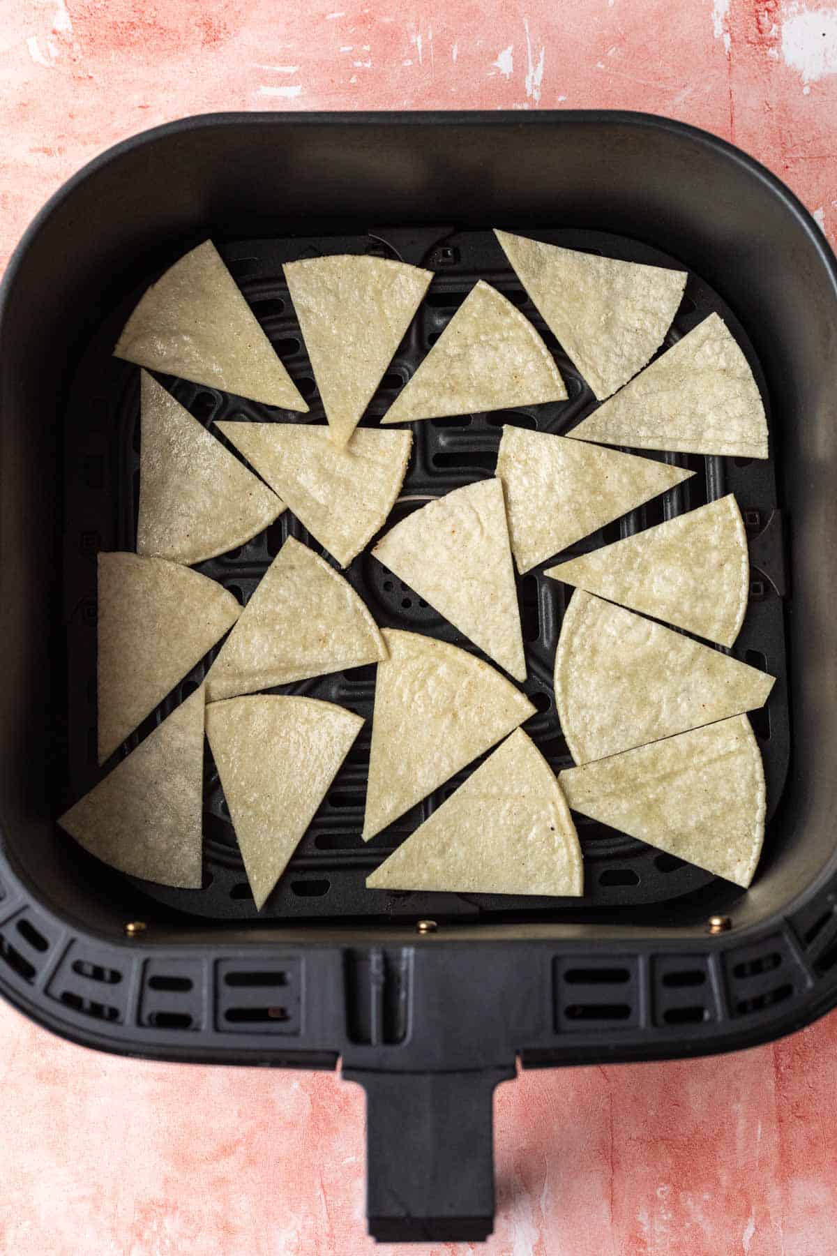 uncooked tortilla chips in the air fryer basket.