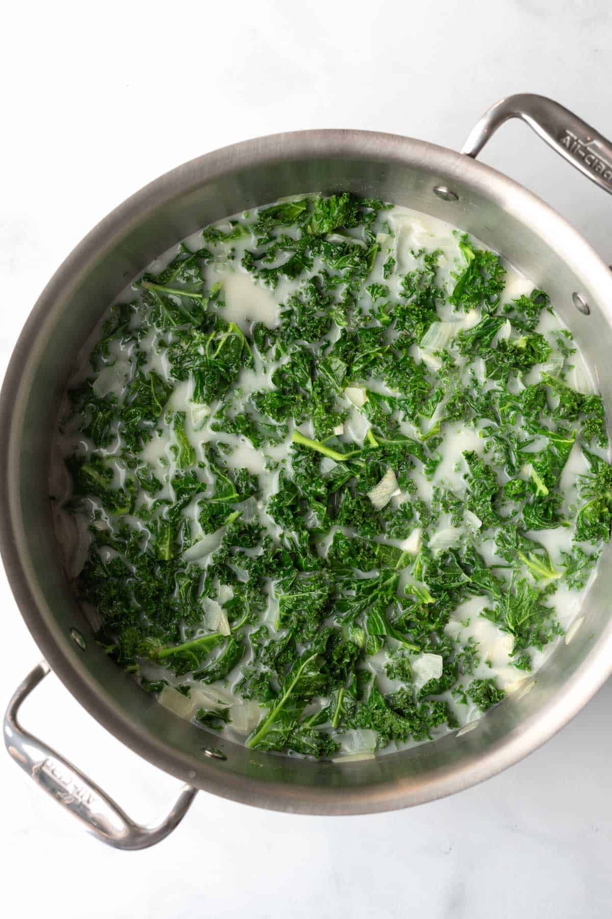 Green kale and light coconut milk are added and the soup is brought to a simmer.
