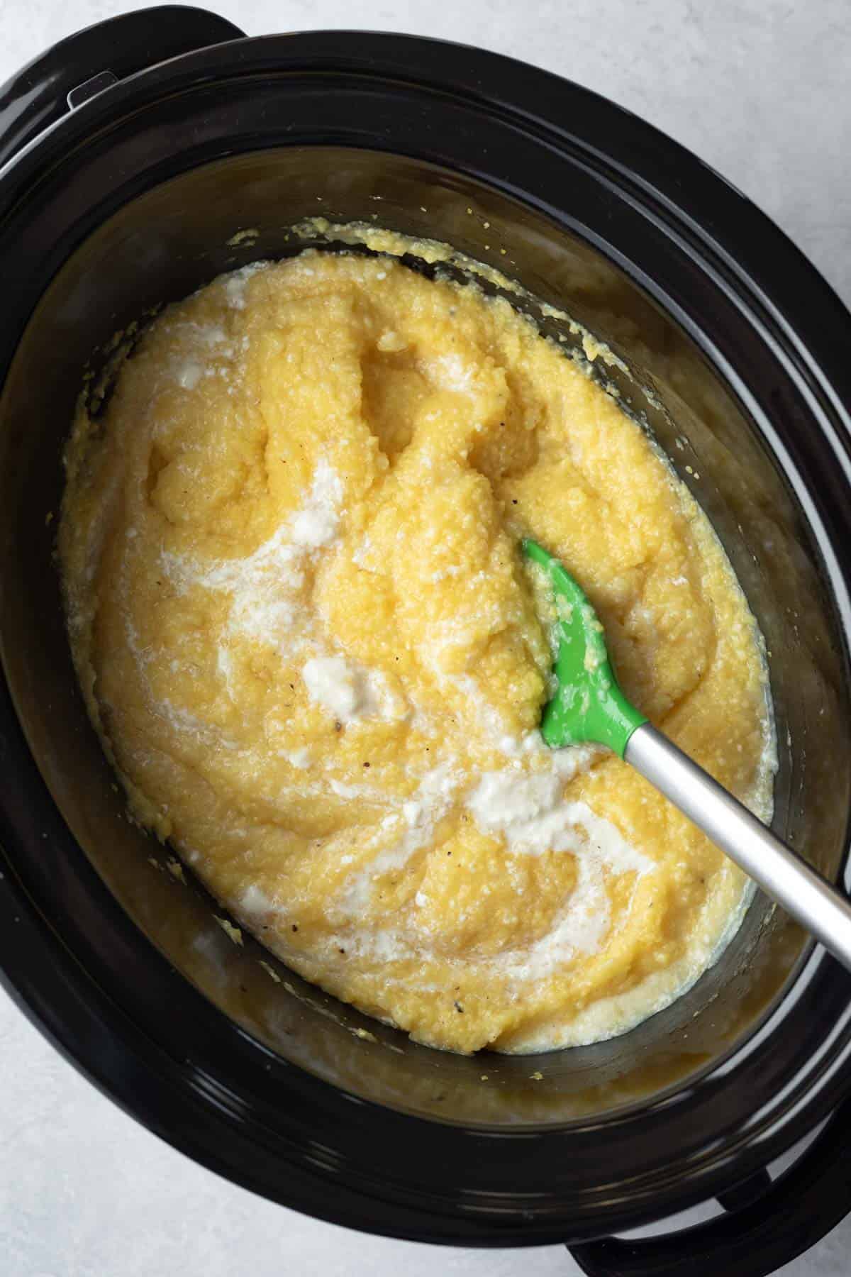 Stirring non-dairy yogurt and butter into the creamy cooked polenta.