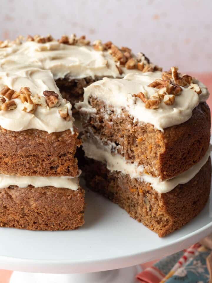 A vegan carrot cake with two layers with homemade frosting in between and on top.
