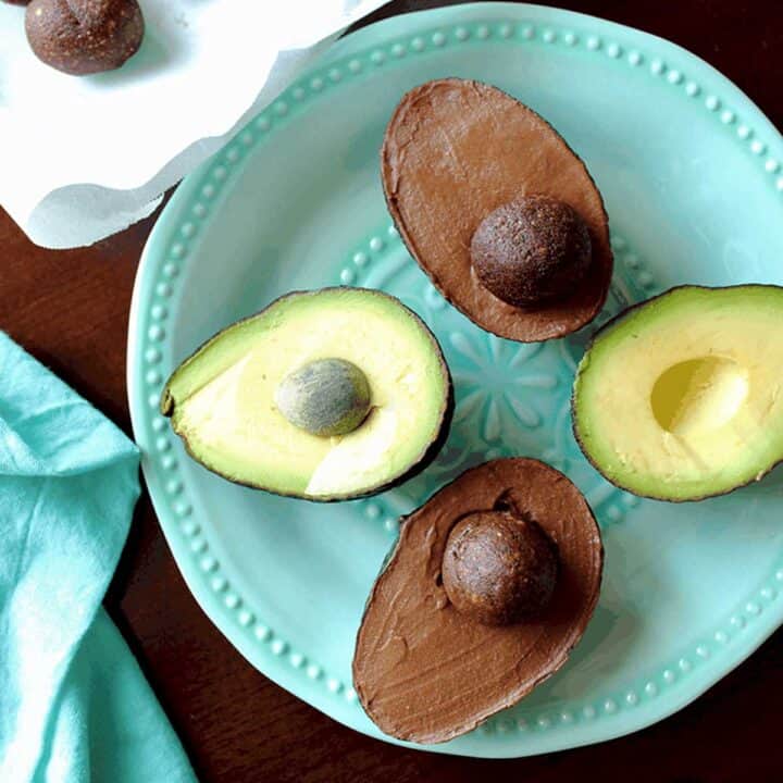 plate of vegan chocolate gelato in two avocado shells with brownie "pits" and two avocado halves.