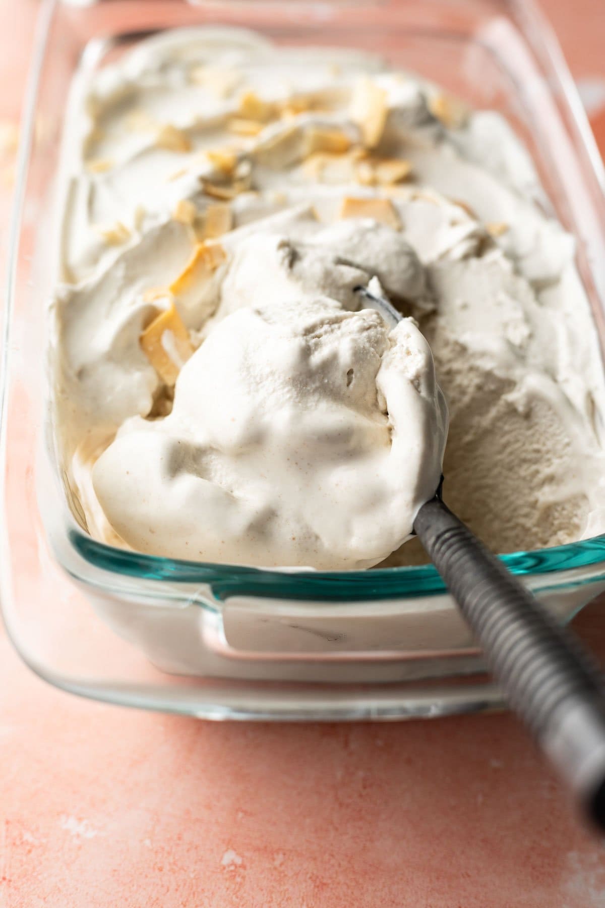 An ice cream paddle scooping up soft and melty vanilla coconut milk ice cream.