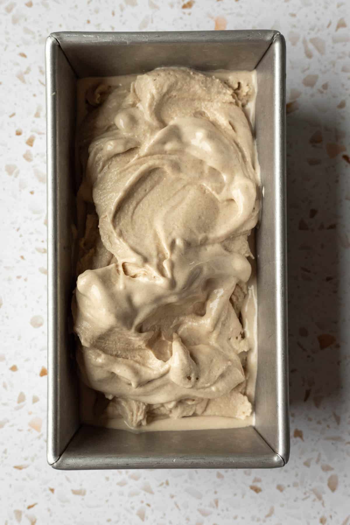 Oat-cashew date ice cream with a soft-serve consistency in a loaf pan.