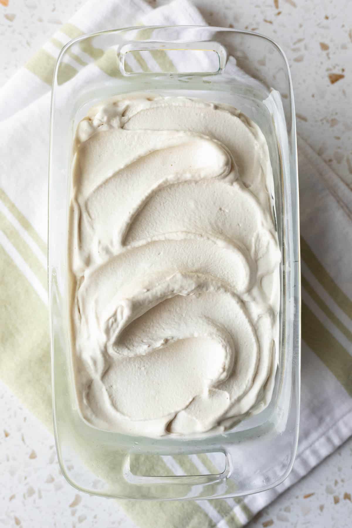 Soft-serve consistency ice cream after churning spread in a glass dish to be frozen.