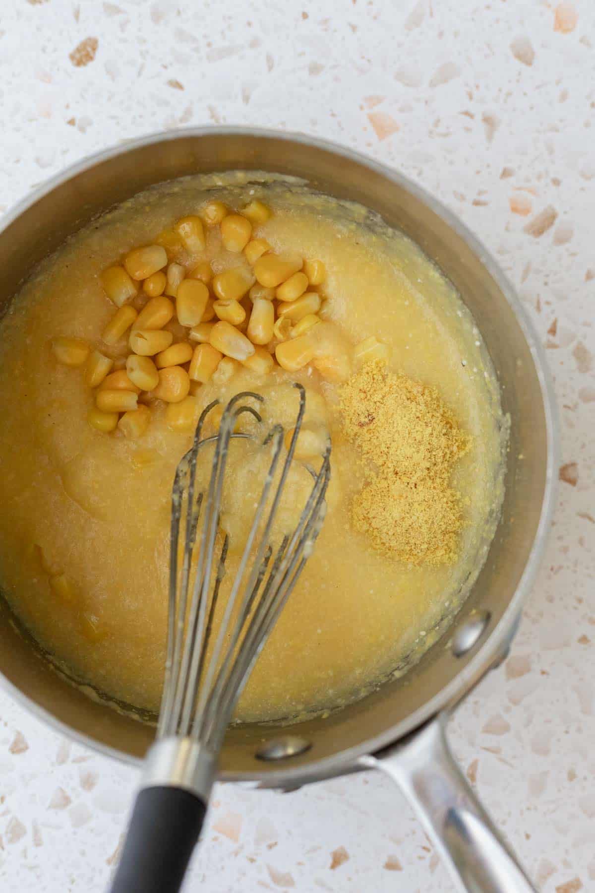 Whisking ingredients into the polenta in a saucepan.