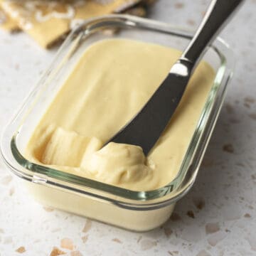 close-up of vegan butter spread in a glass container with a knife.
