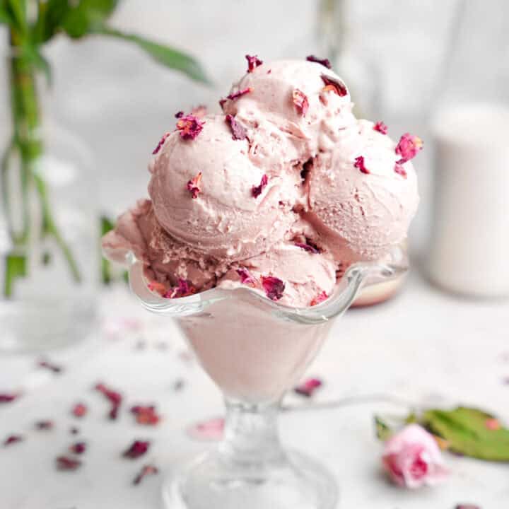 scoops of vegan rose ice cream in a glass sundae dish.