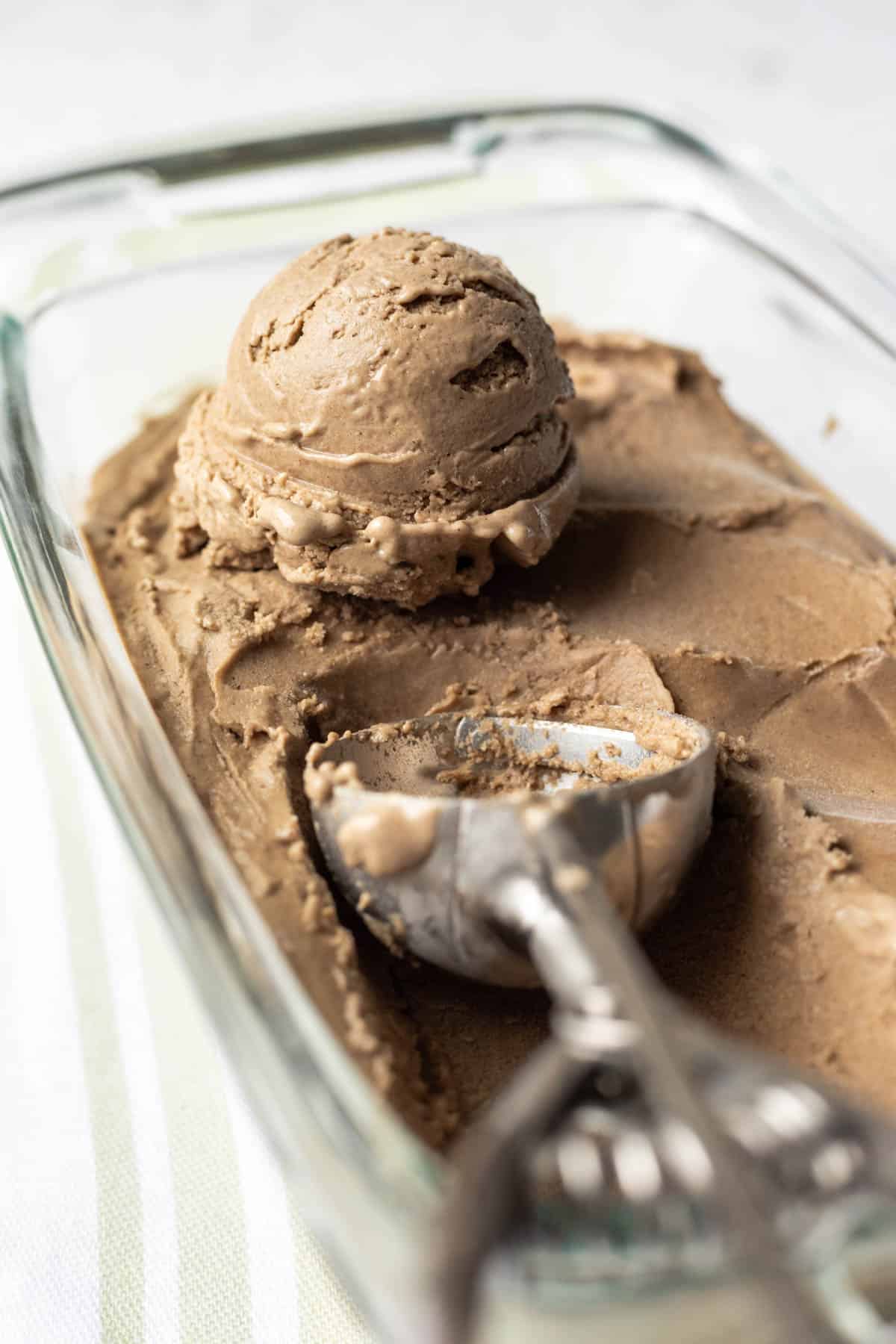 Date sunflower seed ice cream in a glass dish with a scoop resting on top.