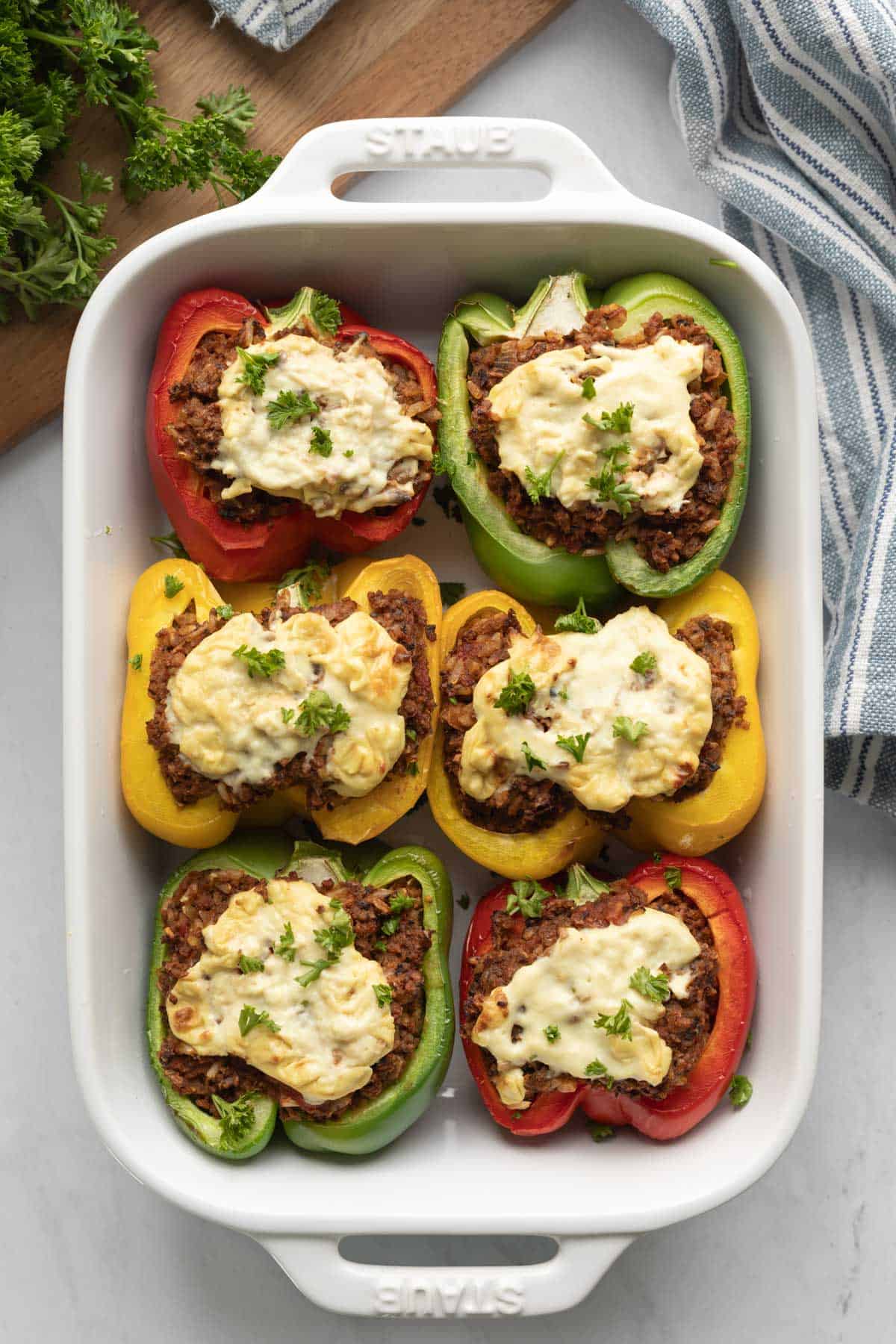 Six vegan beef stuffed peppers in a white baking dish.