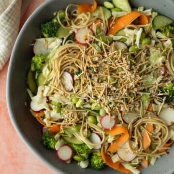 A serving bowl filled with ramen noodle salad and colorful vegetables.