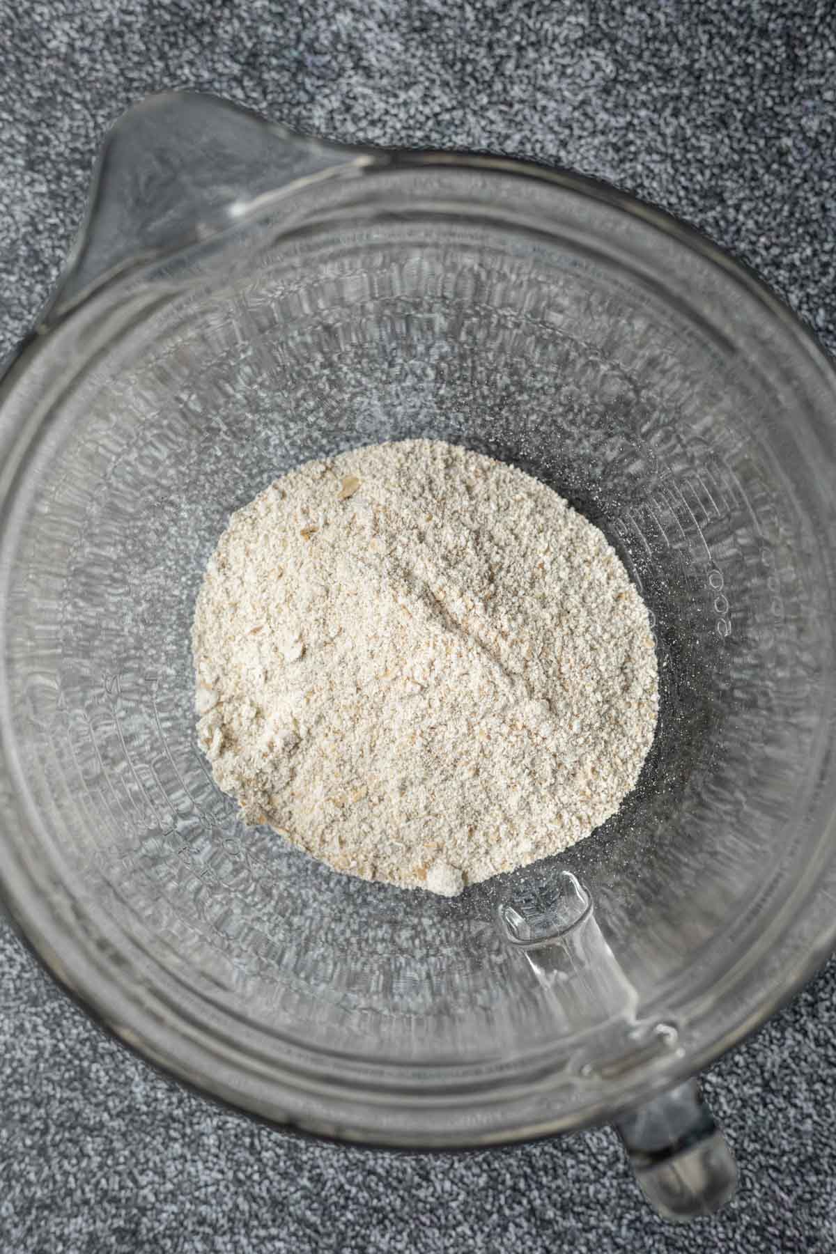 Rolled oats that have been blended into flour in a large mixing bowl.