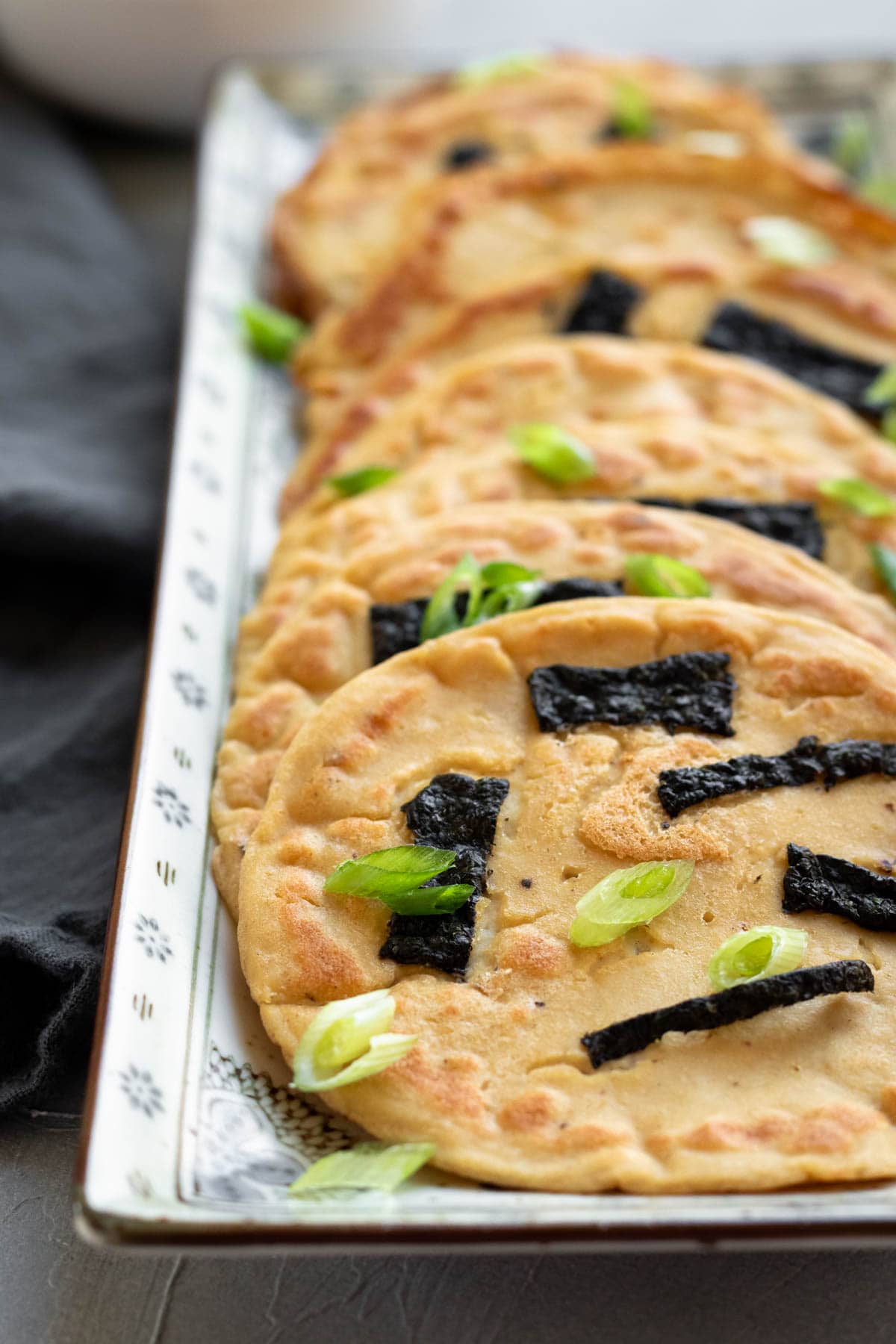 A long rectangular serving plate filled with a row of Asian tofu pancakes.