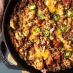 Close up overhead shot of beefy skillet casserole topped with melted dairy-free cheese and pickled jalapenos.