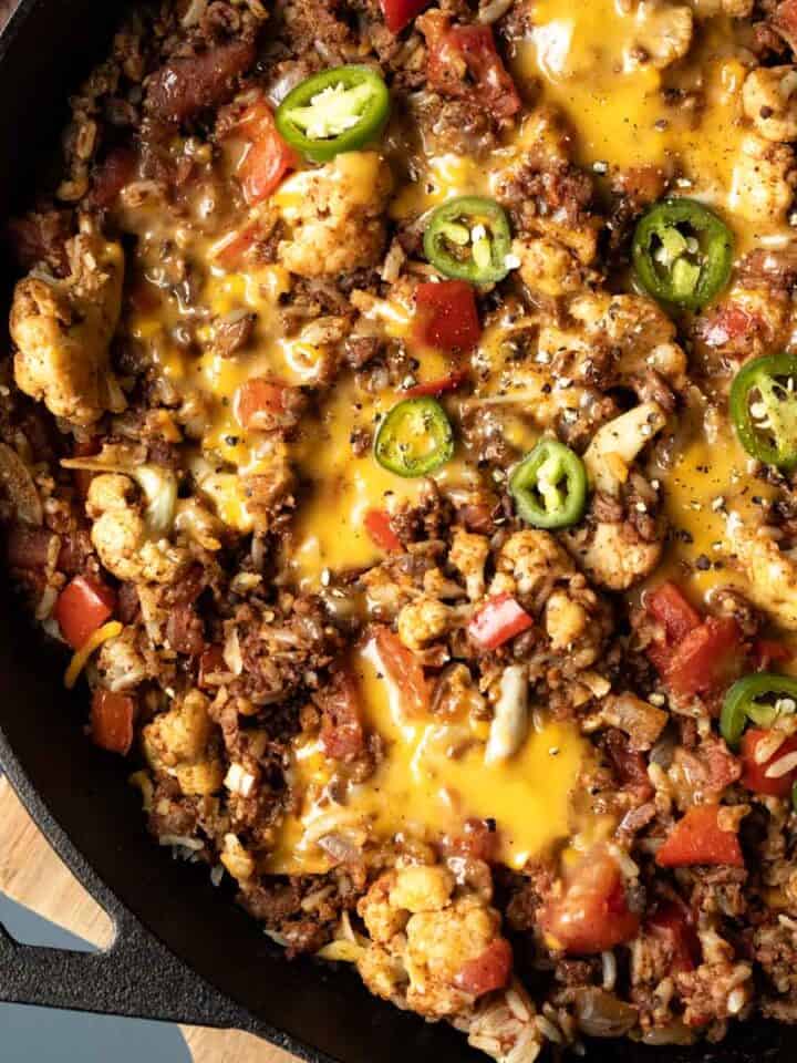 Close up overhead shot of beefy skillet casserole topped with melted dairy-free cheese and pickled jalapenos.