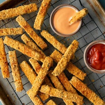 close-up overhead of tofu fries after baking on a wire rack with dipping sauces on the side.