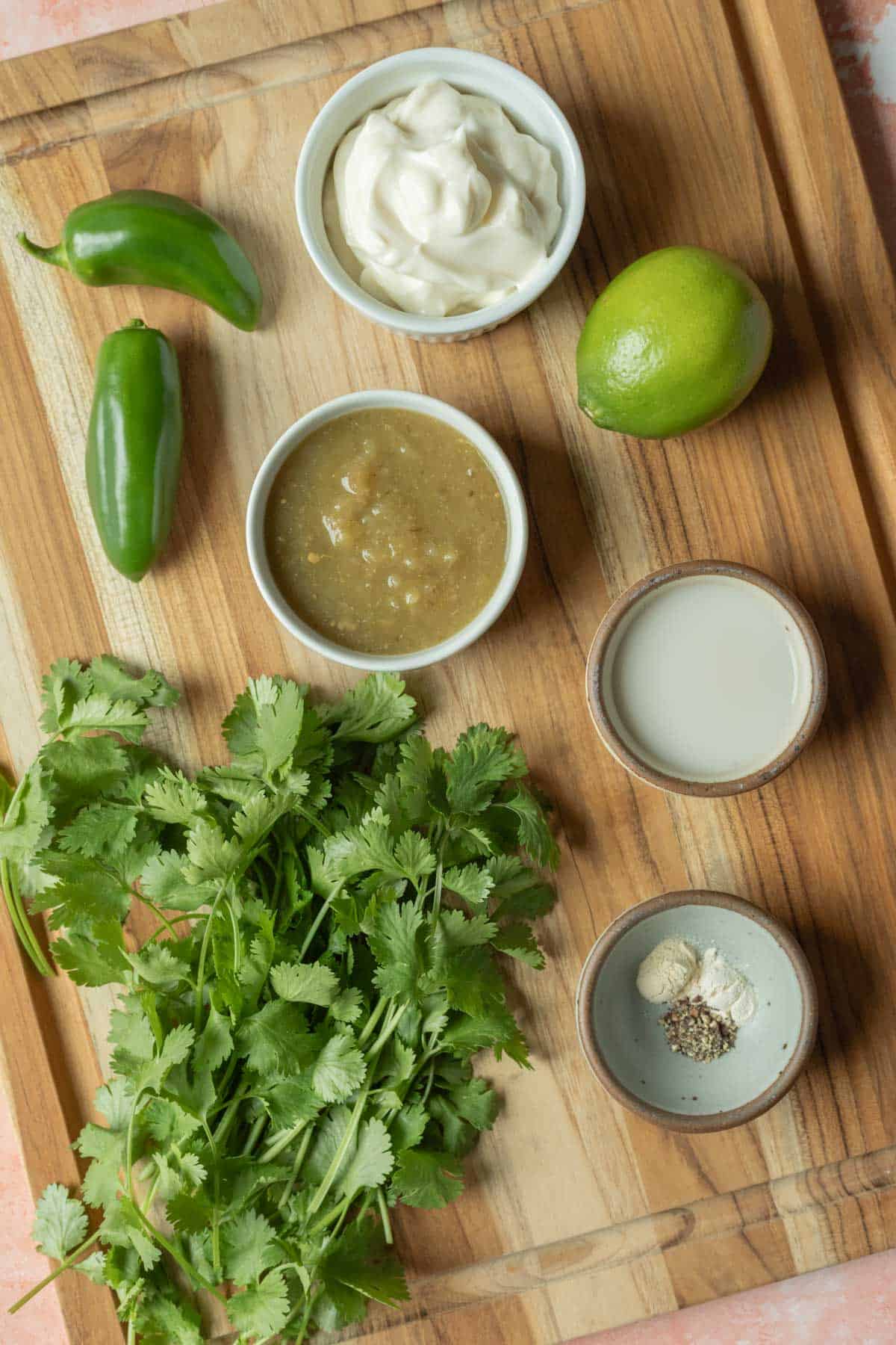 The ingredients needed for jalapeno dressing laid out on a wood cutting board.