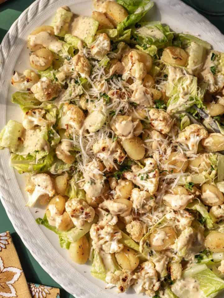 Overhead view of roasted gnocchi salad topped with creamy dressing.