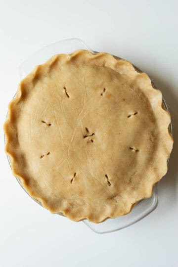 Showing the unbaked apple pie with fluted edges and vent holes cut in the top crust.