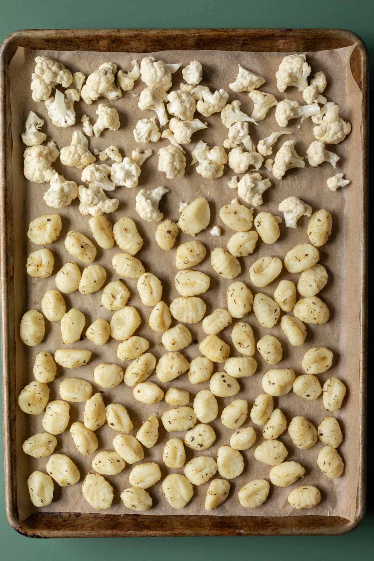 Gnocchi and cauliflower spread out on a sheet pan ready to be roasted.