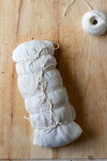 Showing the uncooked seitan wrapped in cheesecloth and tied with twine.