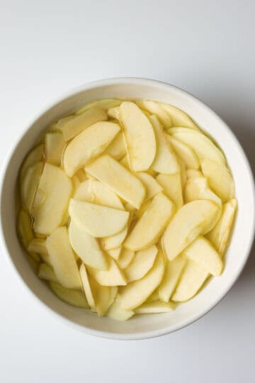 Sliced apples resting in a bowl of cold water with lemon juice.