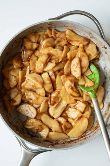 Pre-cooking the apples in a large pan with sugar, spices, and arrowroot starch.