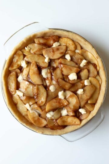 Apple pie filling spooned into the pie plate with cubes of vegan butter dotting the top.