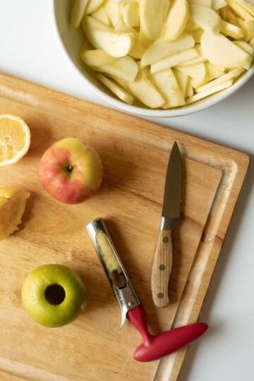 Coring and peeling apples and putting apple slices in a bowl.