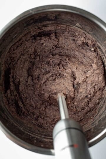 Blending black beans in a pressure cooker with an immersion blender.