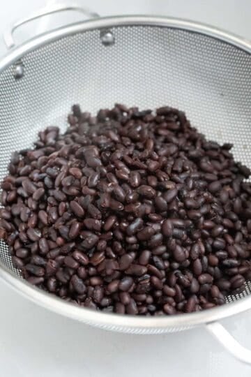 Draining black beans in a colander.