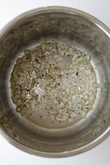 Sauteing onion and garlic in oil in a pressure cooker.