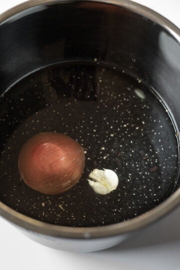 Beans, onion, and garlic, water, and salt added to a pressure cooker.